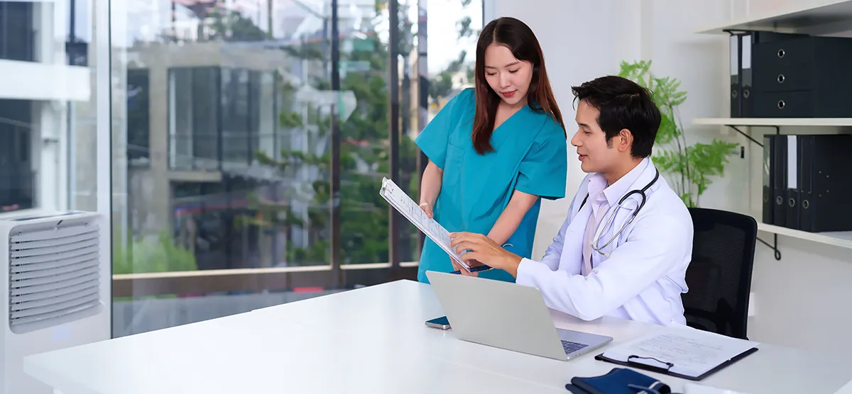 Two professionals reviewing patient ledger reports and monthly collections data in a dental office, representing accurate bookkeeping and cash flow management.